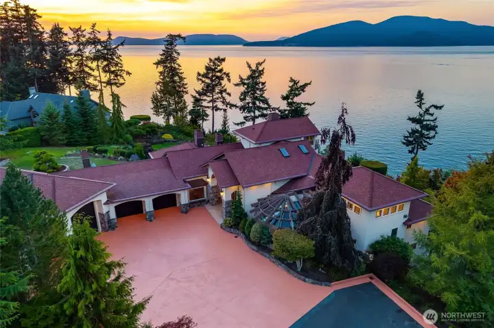 From above, the estate reveals its full grandeur, a nearly two-acre waterside setting bathed in the glow of the evening sun.