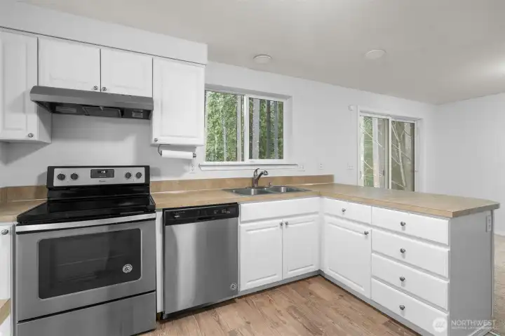 Light filled kitchen with white cabinets and SS appliances