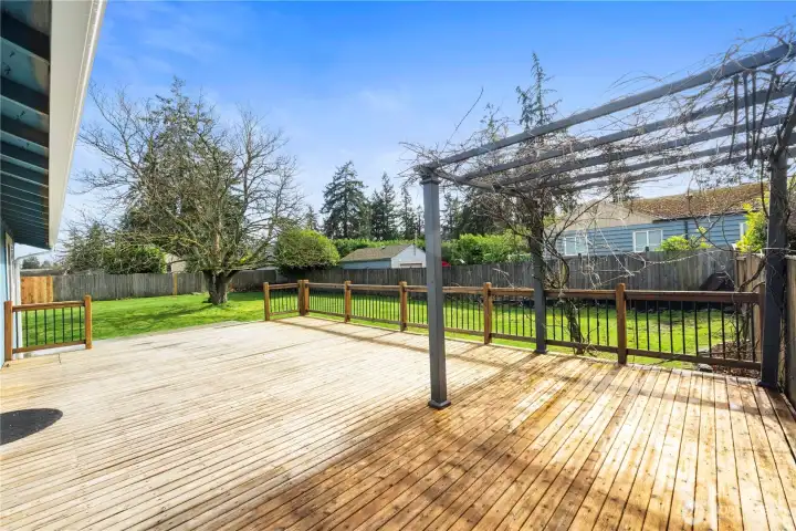 A yellow cedar deck with wrought iron railing and an arbor provides the perfect spot to enjoy summer BBQs.