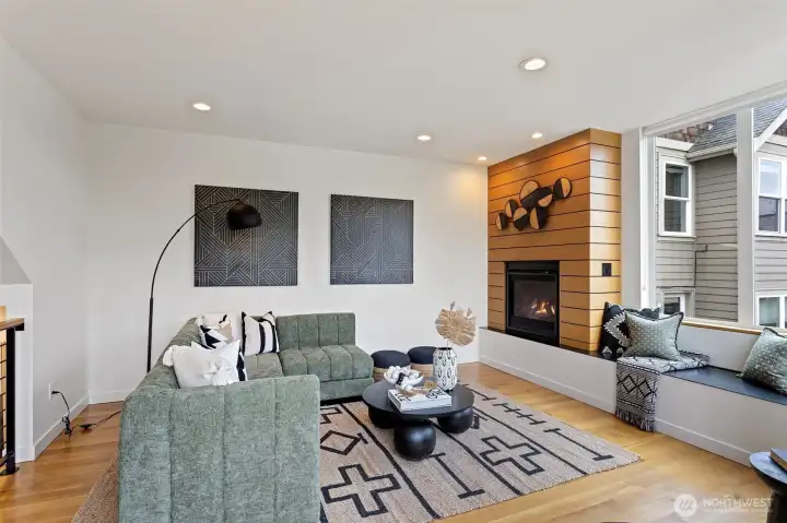 The living room centers around a gas fireplace with modern surround and next to a convenient window seat.