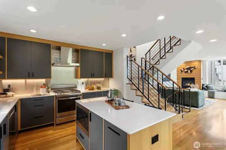 The spacious chef’s kitchen features a center island for eating and gathering.  Just beyond is the dramatic black steel stair railings with rift sawn oak handrails.