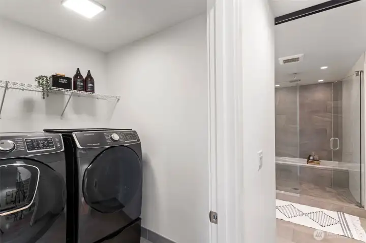 Just outside the Primary Suite is a laundry room with full-sized Samsung front loading washer and dryer on pedestals.