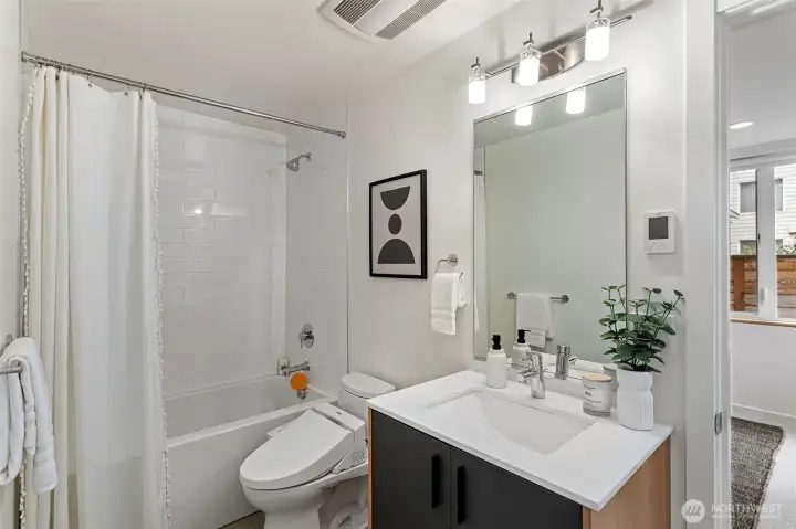 The first level full bathroom has heated tile flooring and a sleek modern design.