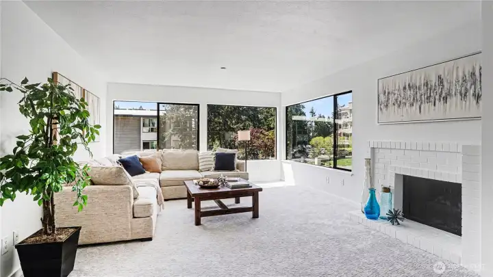 A spacious and inviting living room, complete with a fireplace for cozy evenings and expansive corner windows that fill the home with natural light.