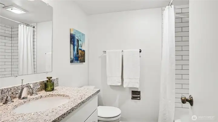 Main full size bathroom with ample counterspace and neutral color palate.