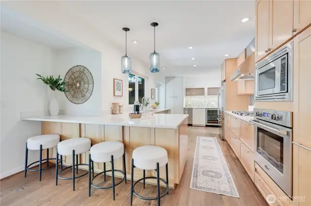A closer look at the stunning kitchen with gas cooktop, slab quartz countertops, stainless steel appliances and beautiful wood cabinetry for warmth and classic style.
