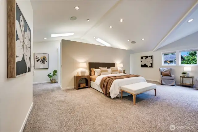 Sumptuous primary suite with cathedral ceilings, skylights in the walk-in closet, seating area and custom built-in with beverage cooler.
