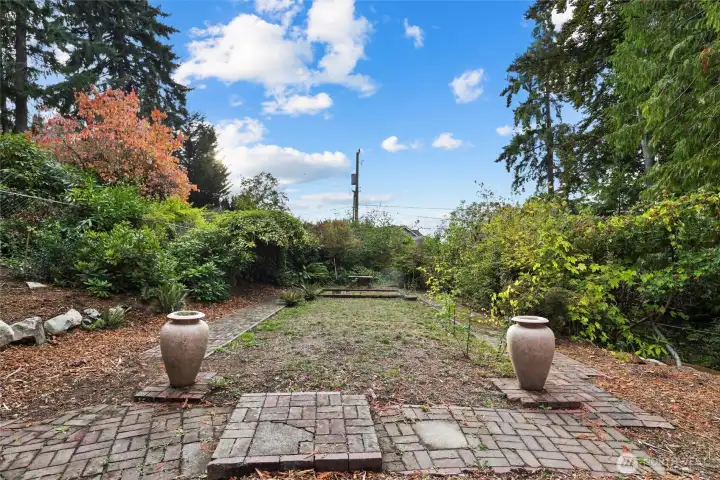 Former rose garden framed by two urns with a pond area that once housed a koi pond, offering opportunity for restoration or new landscaping.