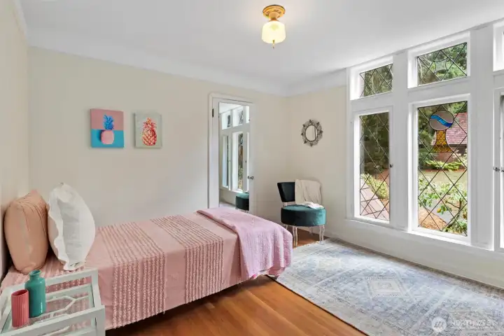 This bedroom features a trio of stained glass windows that fill the space with natural light and showcase historic charm. (and an en suite bathroom)