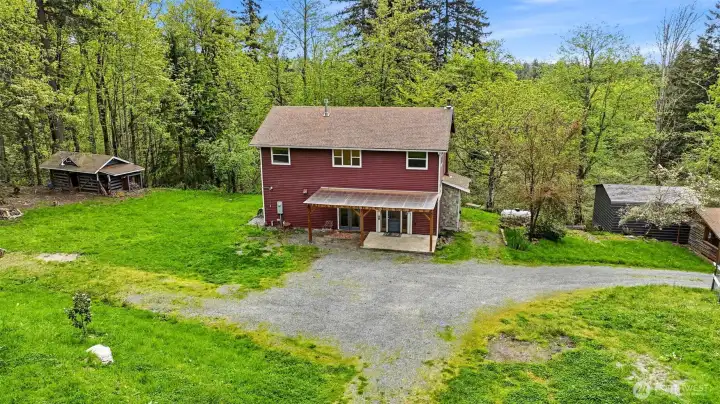 Main house with woodshed on left, and carport and pump house on right