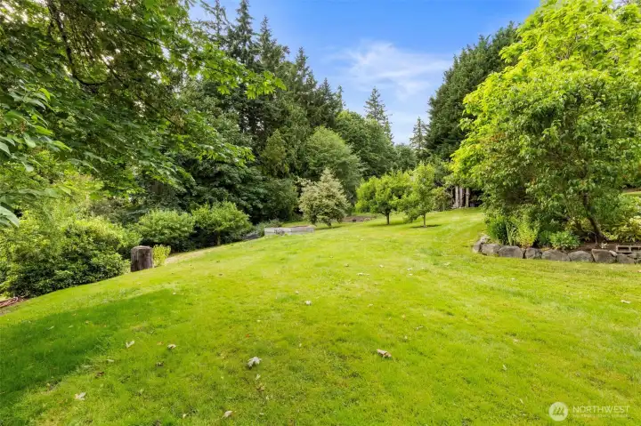 Expansive lawns surrounded by flowers and fruit trees with views of Liberty Bay grace the property. An irrigation well provides free water.