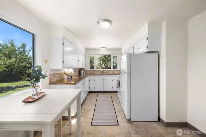 This charming kitchen features tons of storage and countertop area, tile backsplash, windows to the back yard.