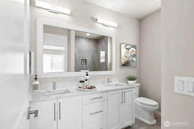Primary bathroom with thick slab quartz counters, double undermount sinks and a large fully tiled shower.