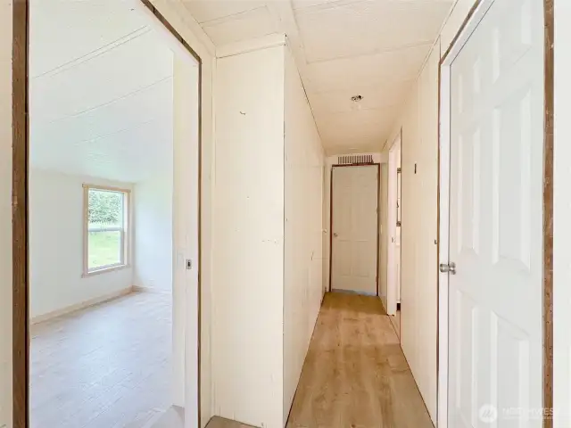 Looking down the hall and the first bedroom on the left. Primary is at the end of the hall. Notice Vaulted ceilings  in the bedroom.