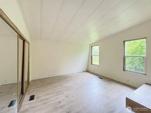 Primary bedroom with double closets. Windows look out into trees.