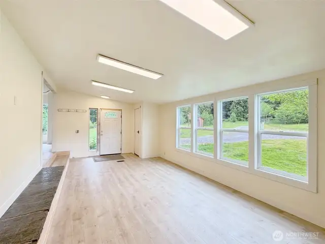 Living room with vaulted ceilings, and wall of windows for light.