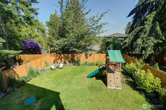 Large backyard, fully fenced in, with mature grass and landscaping, fully sprinklered