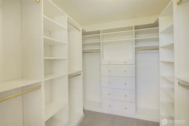 Primary closet with built-in shelves and cabinets