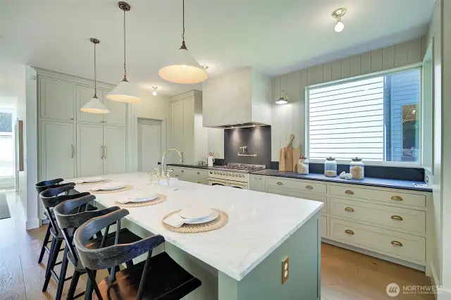 Luxury Chef's kitchen with Carrara marble island, soapstone countertops, pendant lights above island imported from England, custom handmade cabinetry with brass hardware, built-in coffee station, lime wash hood over imported ILVE range from Italy, custom-panel refrigerator from Fisher & Paykel, Rejuvenation light fixtures