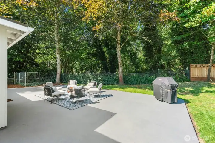 French doors off the great room open to a brand-new, oversized concrete patio — ideal for entertaining — and the fully fenced backyard backs to a forested greenbelt with a sprawling lawn.