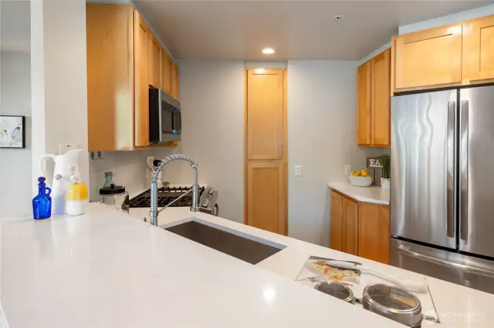 The chef's kitchen is stylishly appointed with white quartz countertops, newer stainless steel appliances, and a gas range.