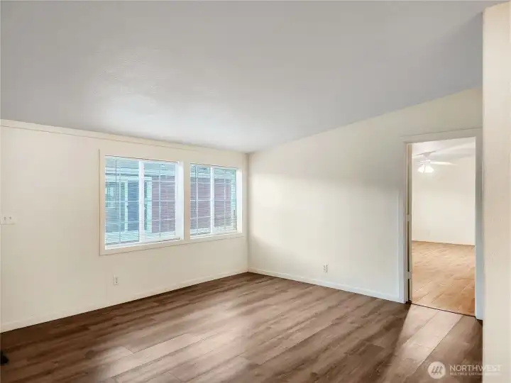 The living room features durable vinyl plank flooring and a versatile layout—perfect for a formal sitting area, home office, or cozy den.