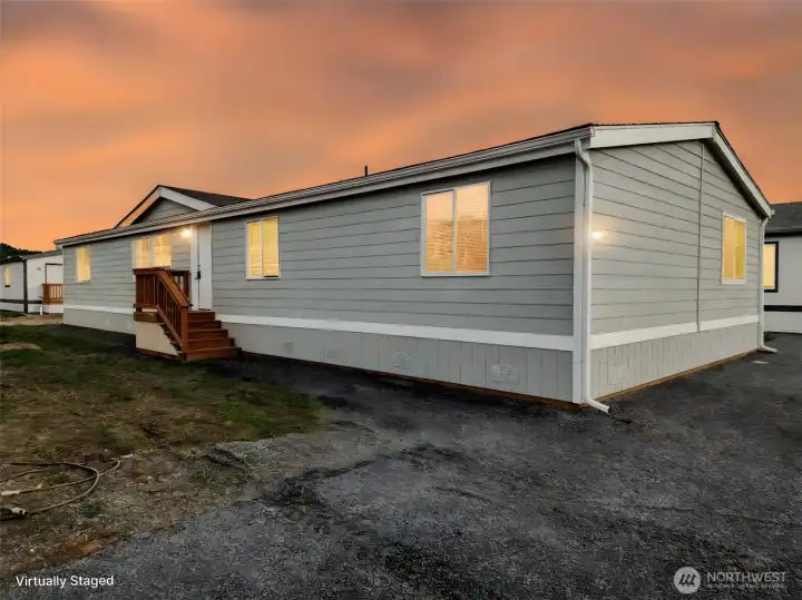 Captured at golden hour, the sky glows in warm hues as light spills softly from the windows—creating a cozy, welcoming glow that invites you home.