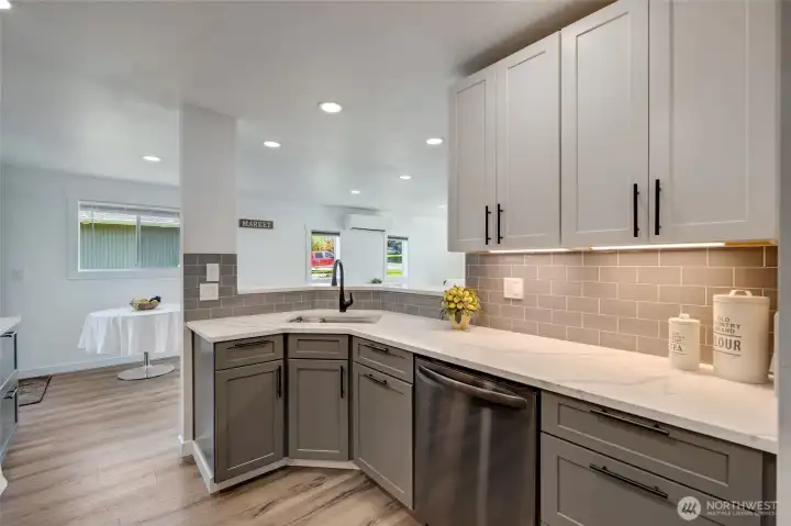 The kitchen features quartz countertops, new cabinetry, black stainless appliances, under cabinet lighting, offering both modern style and everyday functionality.