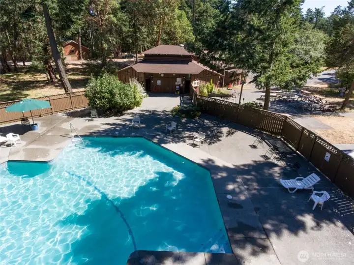 Community pool and clubhouse setting surrounded by mature evergreens, offering residents a peaceful retreat just moments from the waterfront.