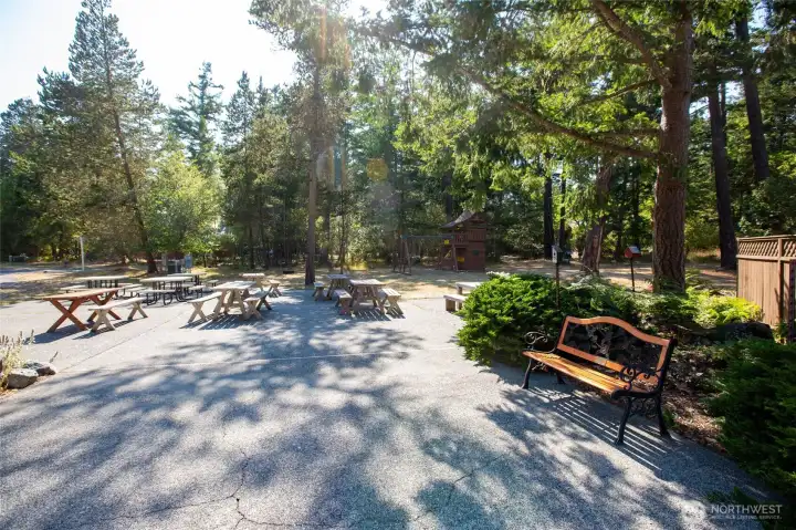 Shared outdoor gathering space with picnic tables and play area, perfect for relaxing, entertaining, or enjoying island living within a welcoming community.