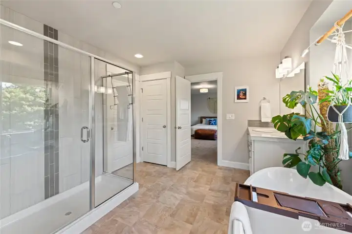 View looking back towards the primary suite living space. The door to the immediate left after the shower leads to the walk-in closet. The other door is additional bath storage (closet).