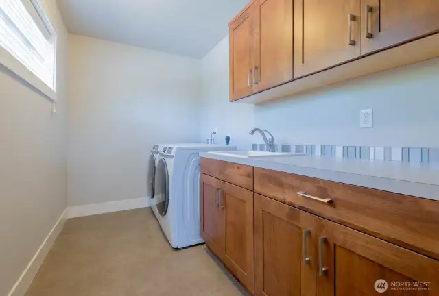 Upstairs the generous laundry room features plenty of storage and counter space and utility sink