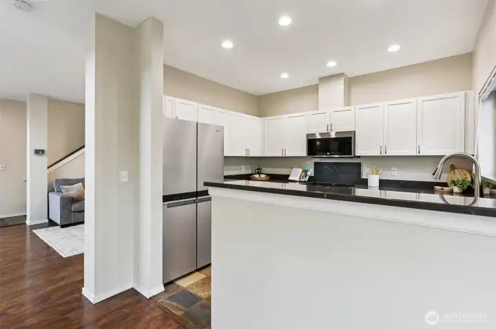 Fresh, light-filled kitchen with sleek countertops, abundant cabinetry, and a convenient breakfast bar—open to the living space for easy, everyday living and entertaining.
