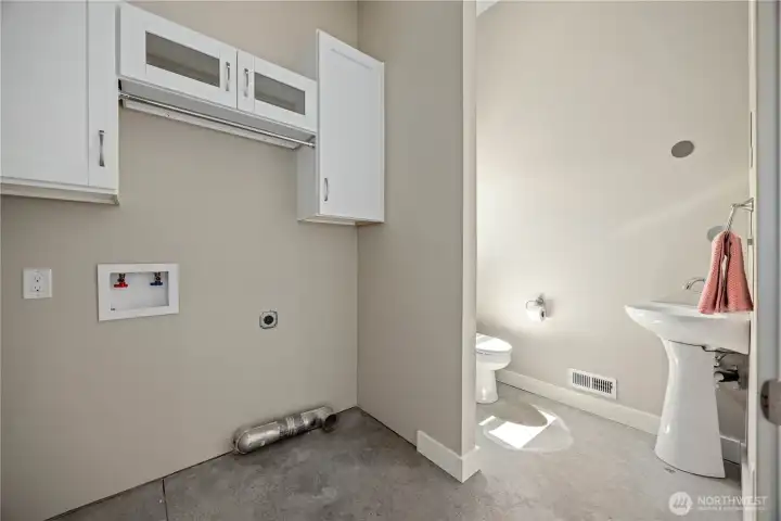 Functional laundry and half bath combination with additional storage, durable concrete flooring, and convenient access.