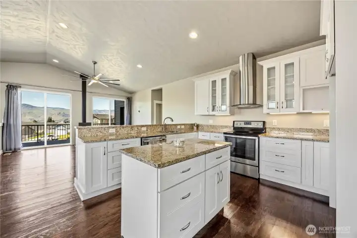 Gourmet kitchen with granite countertops, glass tile backsplash, vaulted ceilings, under-cabinet lighting, and stunning valley views in East Wenatchee.