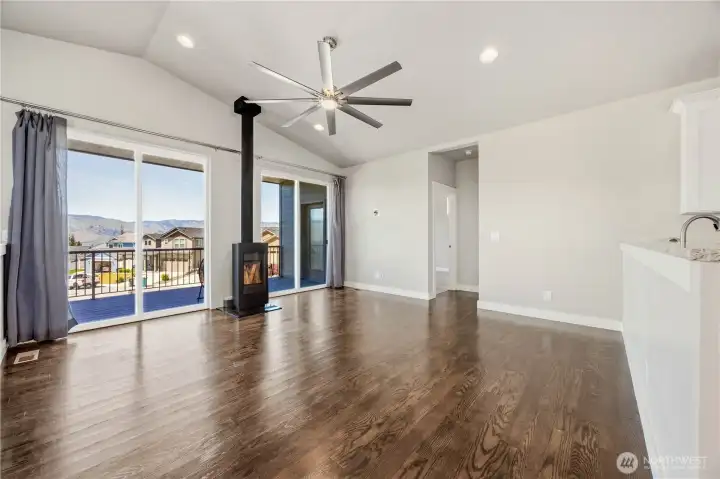 Inviting living room with vaulted ceilings, wood-burning stove, expansive windows, and breathtaking 180-degree valley views