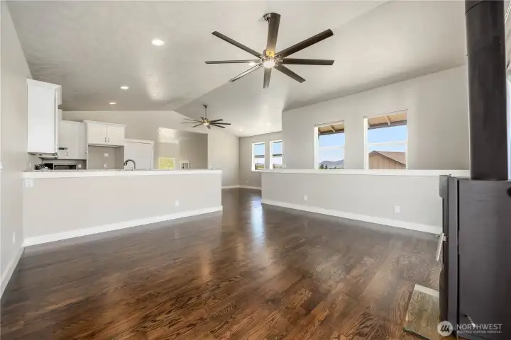 Inviting living room with vaulted ceilings, wood-burning stove, expansive windows, and breathtaking 180-degree valley views