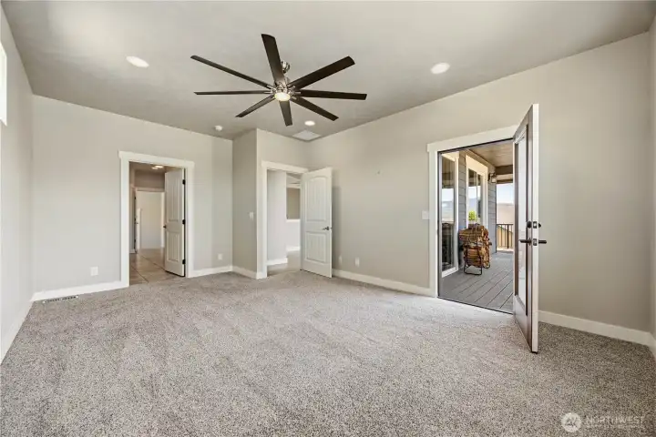 Primary bedroom featuring vaulted ceilings, abundant natural light, and direct access to outdoor living space.
