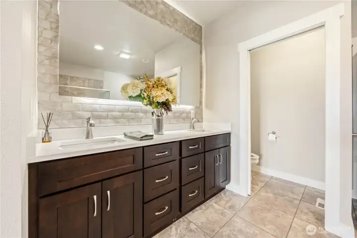 Primary bathroom with dual vanities, built-in storage, soaking tub, and relaxing spa-like design.