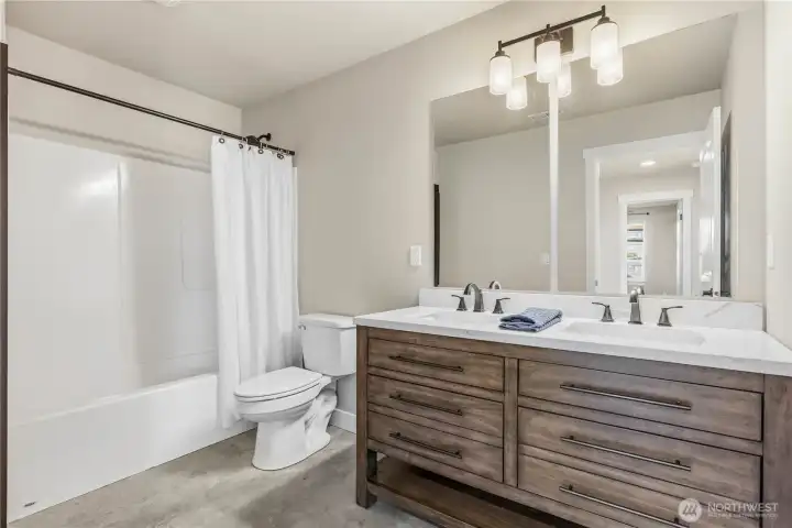 Spacious main bathroom with double sinks, tub/shower combination, and convenient access for guests or additional bedrooms.