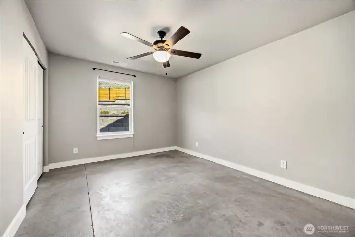 Lower-level bedroom with natural light, overhead fan, and spacious layout for family or guests.