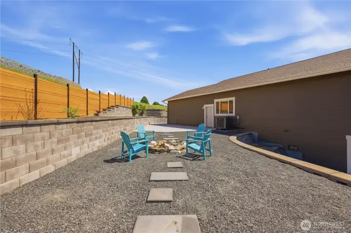 Backyard entertaining area with fire pit, artificial turf, retaining walls, and incredible sunset views.