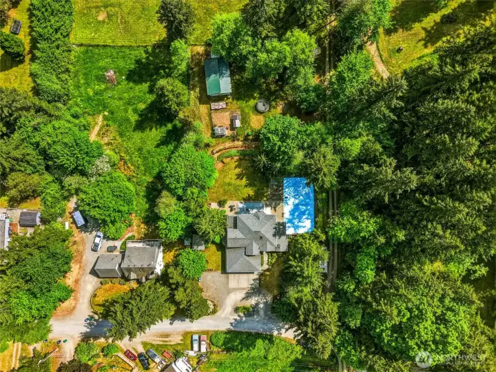 Overhead aerial showcasing full property layout, including home, shop, yard, and surrounding acreage.