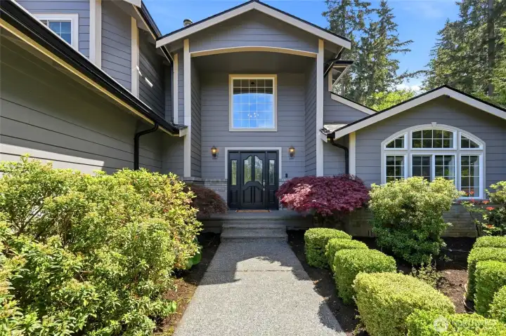 Inviting front entry with manicured landscaping and welcoming walkway leading to this custom Enumclaw home on acreage.