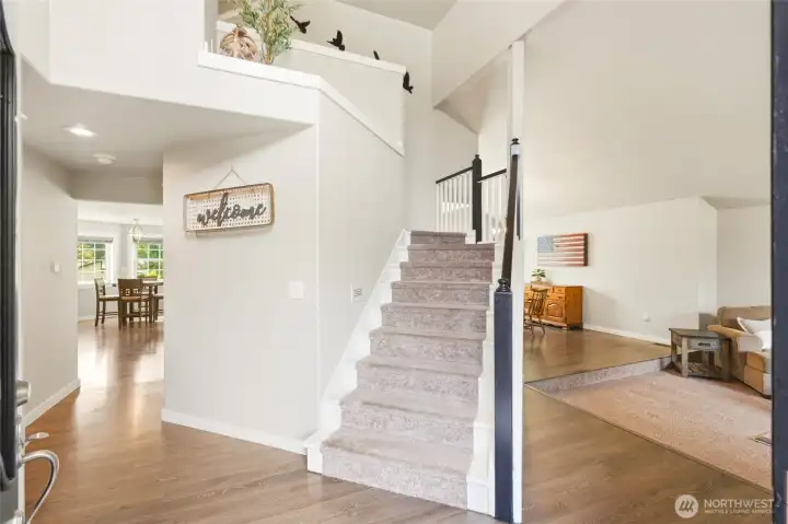 Grand entryway with vaulted ceilings, open staircase, and abundant natural light creating a bright first impression.