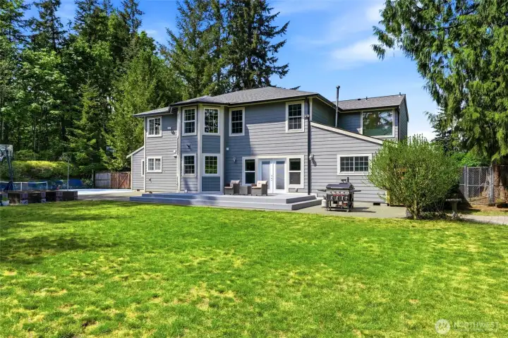 Expansive backyard with lush lawn and mature trees offering privacy and usable outdoor space.