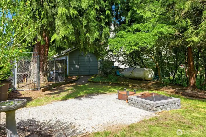 Fire pit area with outdoor gathering space surrounded by trees, perfect for relaxing evenings.