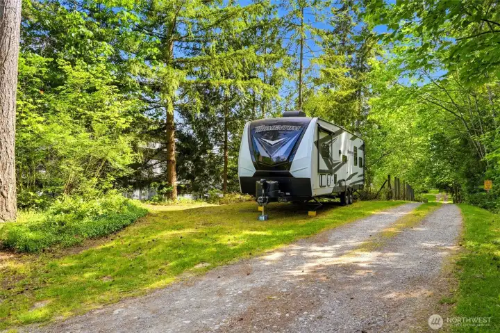 Side driveway with RV parking and access to back gate and shop, offering convenience for recreational vehicles and additional parking.