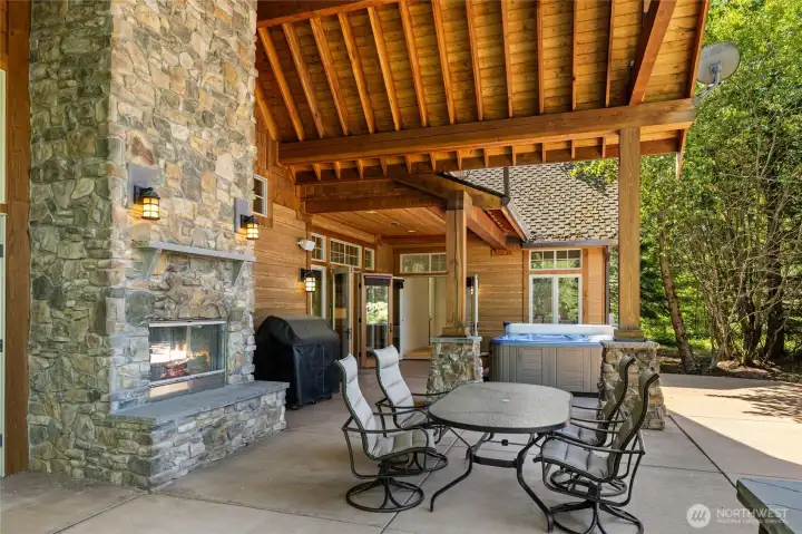 Covered outdoor living space with fireplace and dining space