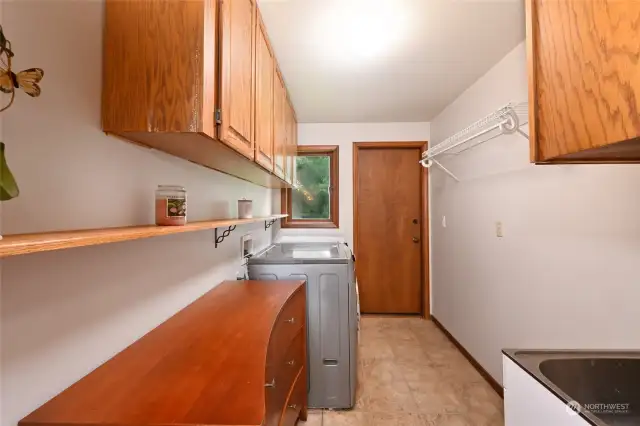 Well-equipped laundry area with a utility sink, plenty of storage, and backyard access